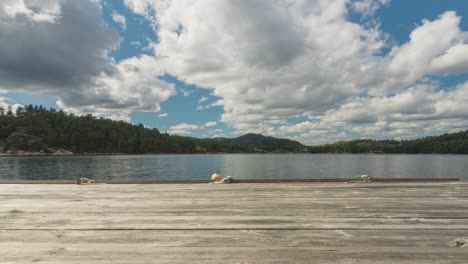 time lapse of clouds forming over countryside lake, wooden pier dock
