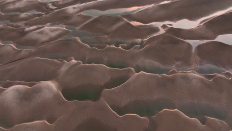 aerial view of sand dunes and water at sunset