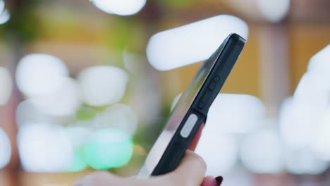 close-up of a phone being operated, with vibrant bokeh light effects in the blurred background, creating a modern and dynamic feel, the side profile of the phone is visible