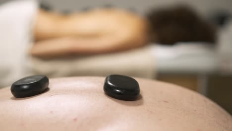 masseuse placing two hot stones on client's back