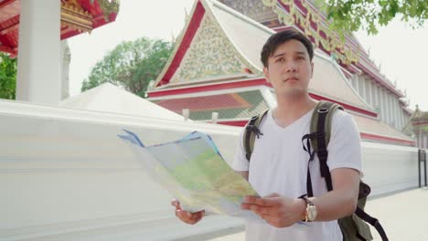 traveler asian man direction on location map in bangkok, thailand, backpacker male looking on map find landmark while spending holiday trip. lifestyle men travel in asia city concept.