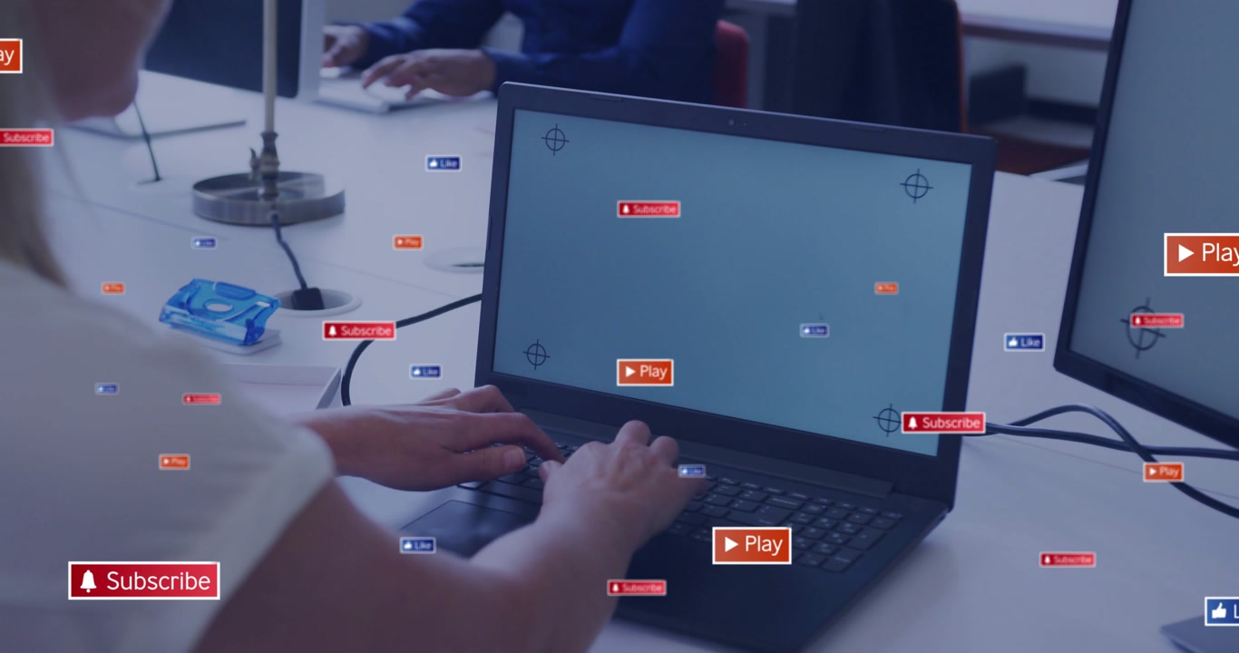 Vertical video: Woman typing on laptop, causing Play Subscribe badges spreading across desk for ads