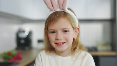 smiling girl with easter bunny ears in kitchen