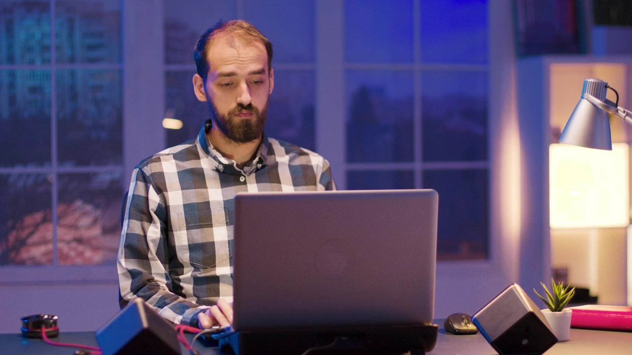 Uomo concentrato che lavora al laptop nel suo home office di notte