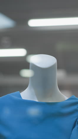 primer plano de un maniquí vestido con una elegante camiseta azul exhibido en una tienda minorista bien iluminada con interior moderno y luces parpadeantes suaves en el fondo