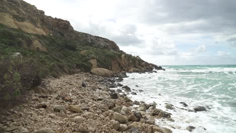caminar sobre rocas cerca de la playa de golden bay en invierno en malta en un día soleado y ventoso