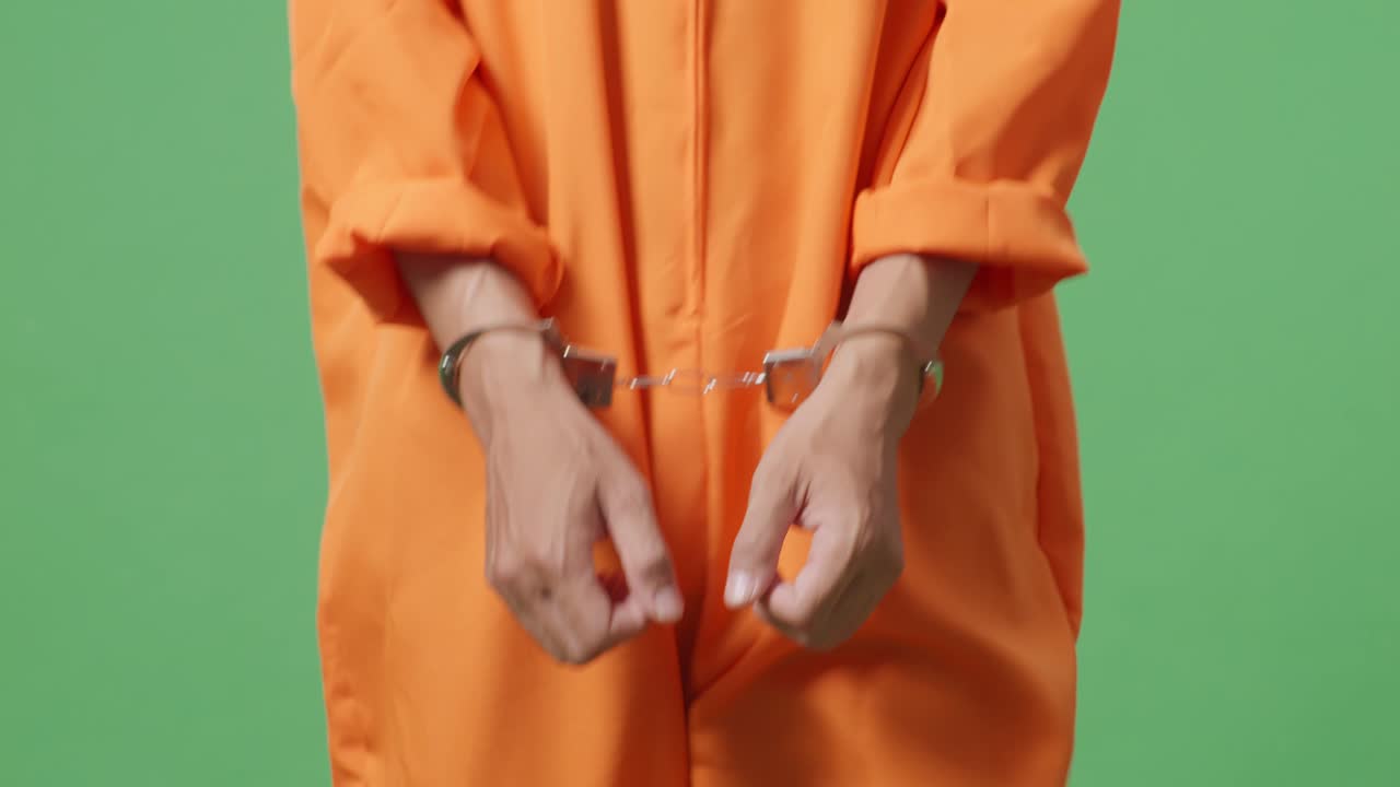 cerca de las manos del prisionero masculino en esposas mientras camina en el fondo de la pantalla verde