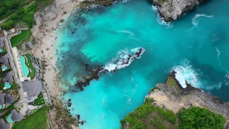 olas turquesas rompiendo en una playa rocosa en la laguna azul en la isla nusa ceningan, vista aérea de arriba hacia abajo