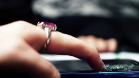 a close-up view of a hand gently touching a smartphone, highlighting the delicate interaction with a beautiful ring adorning the finger