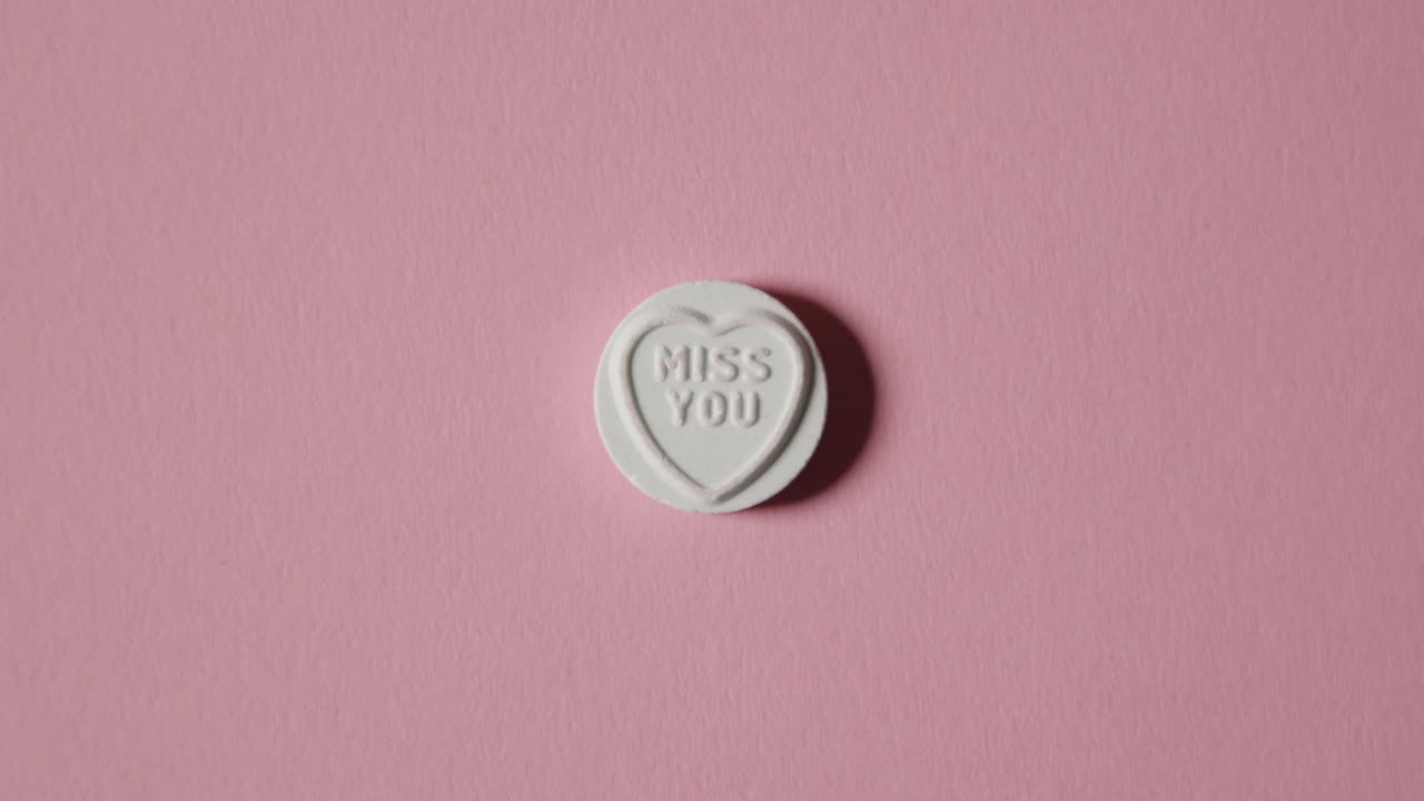 분홍색 배경에 당신이 그리워요 메시지와 함께 심장 사탕을 손에 들고