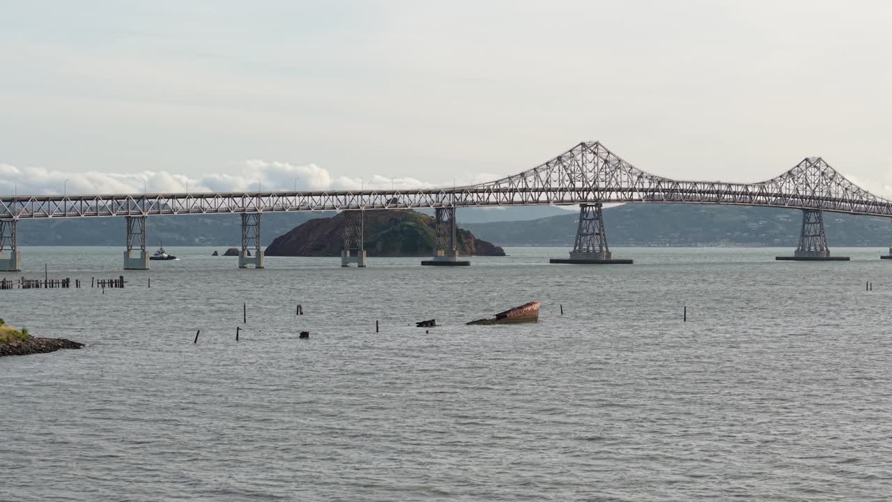 Hovering drone footage captures a full panoramic view of the bridge, its surroundings marked by soft light and coastal detail.