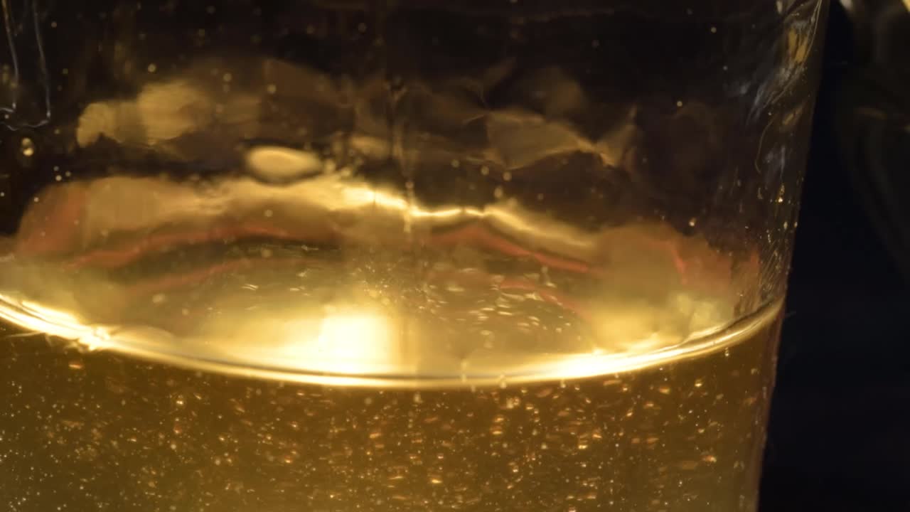 Golden runny honey pouring into a jar close up shot