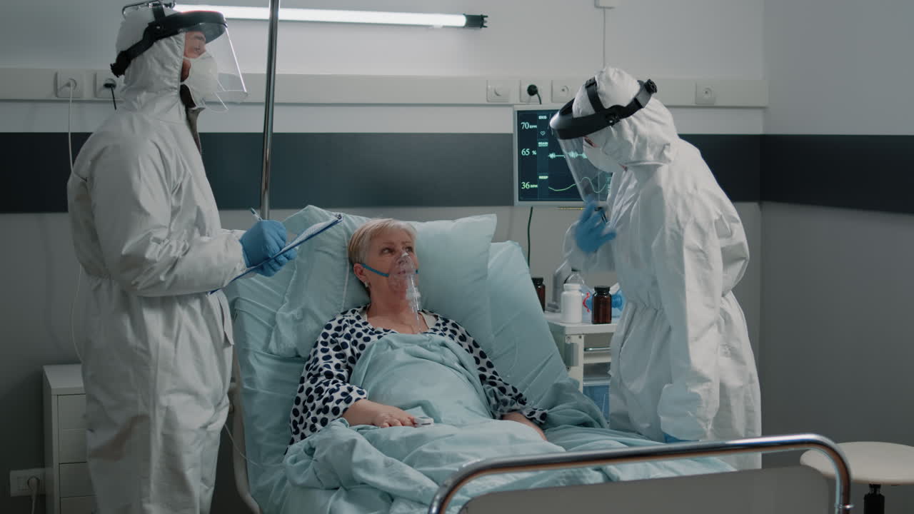 Team of paramedics in hazmat suits checking on patient healthcare