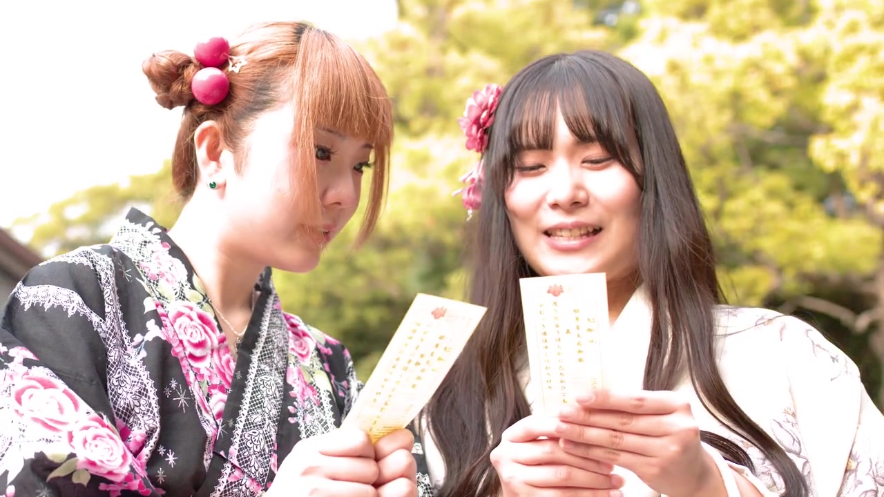 東京の明治神宮で、伝統的な着物を着た二人の女性がおみくじを読む。