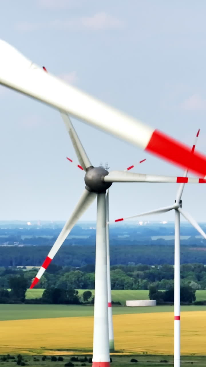 Portrait drone shot of wind power generators collecting energy on a windy day