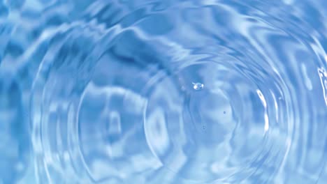 top view slow motion of drop falling into the water surface and diverging circles on white background