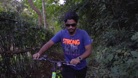 boy man walking with a cycle in deep jungle slow motion front camera