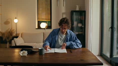 man frustrated while writing at home