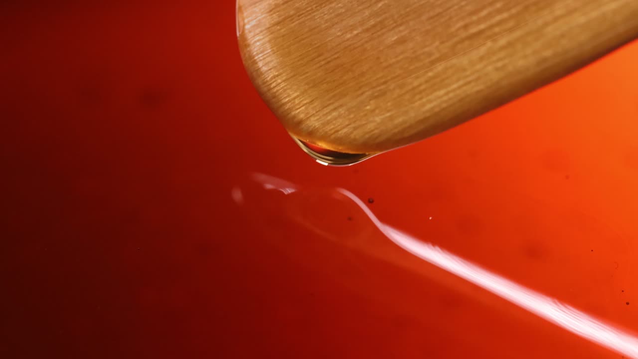 Wooden spatula stirring golden olive oil closeup 4k movie slow motion