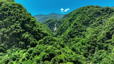 aerial view of crashing waterfall between green lush tropical nationalpark in taiwan during summer