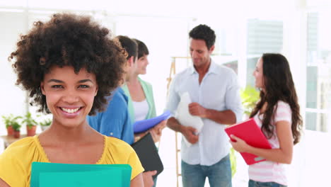 Creative-business-woman-looking-at-camera-with-her-colleagues-behind