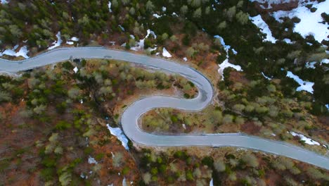 aerial view of drone flying above s curve forest road near alpine mountain peaks pass in spring. patches of snow. video footage with drone stock video