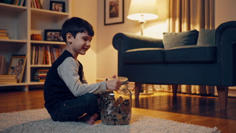 young boy saving money in a glass jar