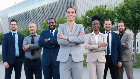 group of multiethnic business people in stylish clothes smiling and looking at camera with arms crossed in the street