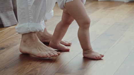 view of tmother and baby feet, mother teaches her son to walk at home