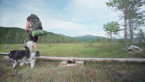 Hombre-Que-Lleva-Una-Gran-Bolsa-De-Camping-Acompañado-De-Un-Perro-Haciendo-Senderismo-En-El-Parque-Nacional-De-Ånderdalen-En-La-Isla-De-Senja,-Noruega