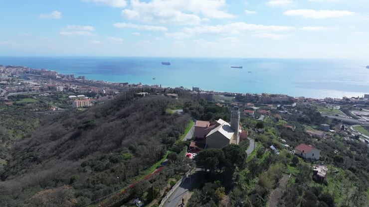 Vista dalla chiesa in cima alla collina su Savona con città, mare, navi e un'atmosfera costiera tranquilla