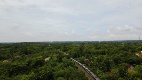vista aérea de un avión no tripulado siguiendo un tren de pasajeros que viaja a través de la indonesia rural