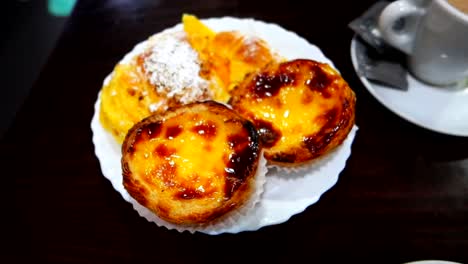 happy woman having breakfast with coffee and traditional portuguese pastries