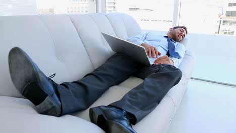 businessman sleeping on couch with his laptop