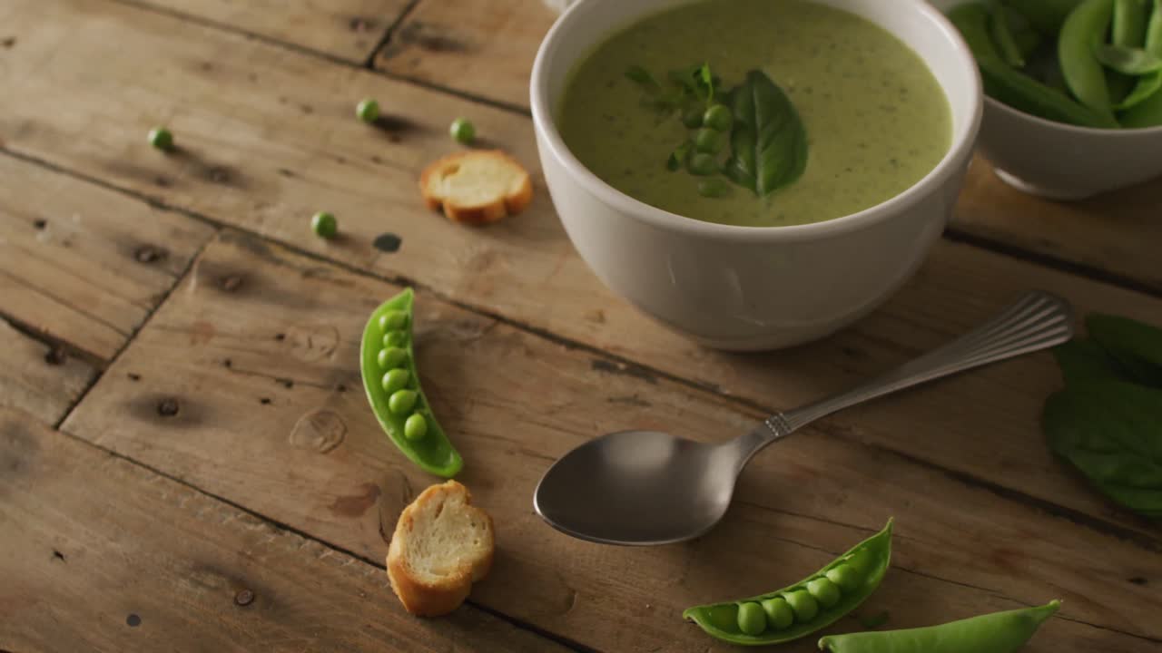video de sopa de guisantes verdes e ingredientes tendidos en una superficie de madera