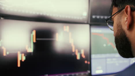 a businessman in a suit looks intently at financial data displayed on multiple computer monitors in an office