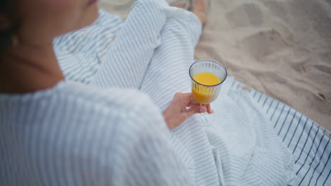 top woman holding juice glass closeup. calm romantic lady resting picnic blanket