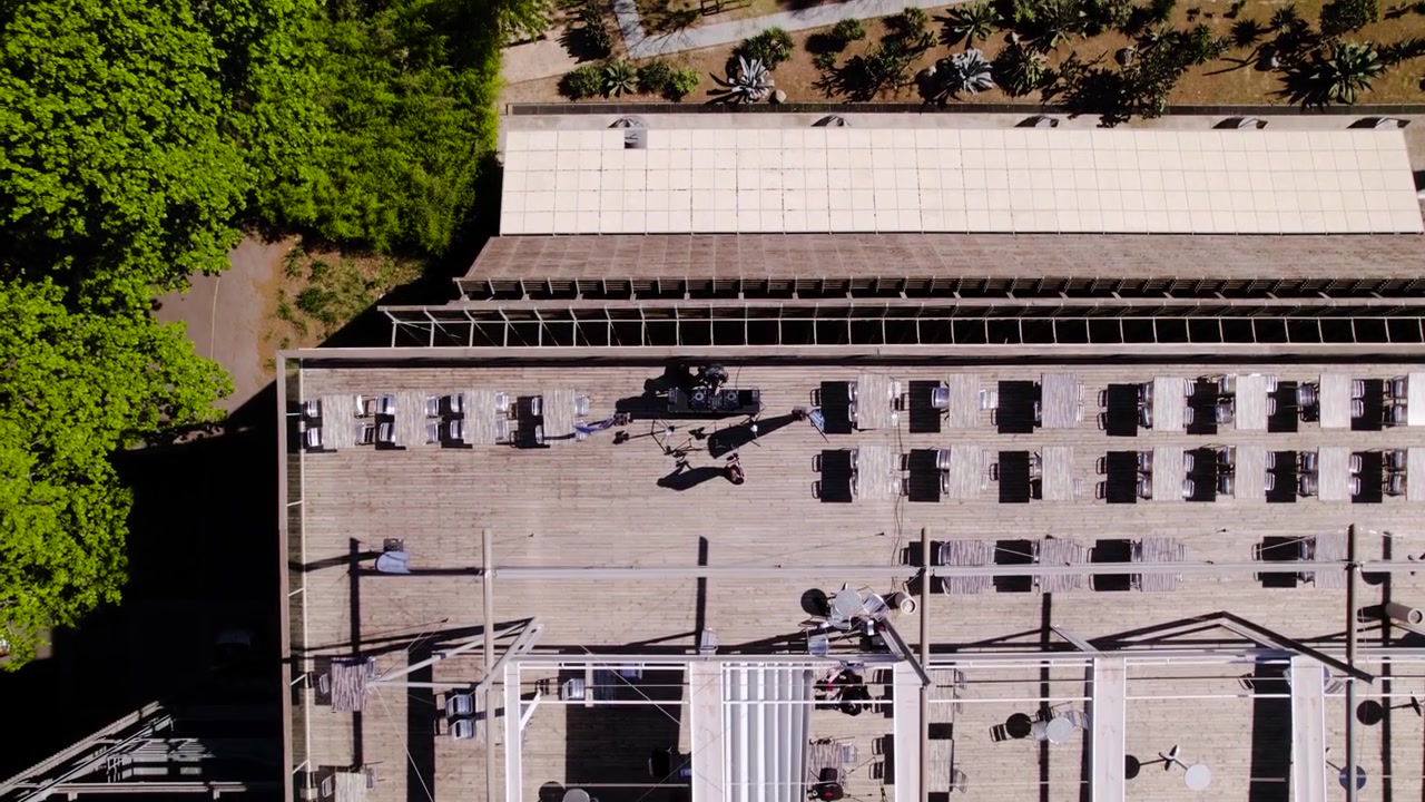 Drone glides over terrace of low rise revealing contemporary exterior