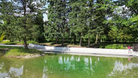 Parque-Verde-Con-Agua-Durante-Un-Hermoso-Día-De-Verano-Rodeado-De-Exuberante-Vegetación-Y-Césped