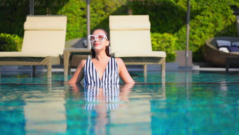 Mujer-Joven-De-Moda-En-Traje-De-Baño-Tomando-El-Sol-En-La-Piscina-Del-Resort-Tropical-De-Lujo