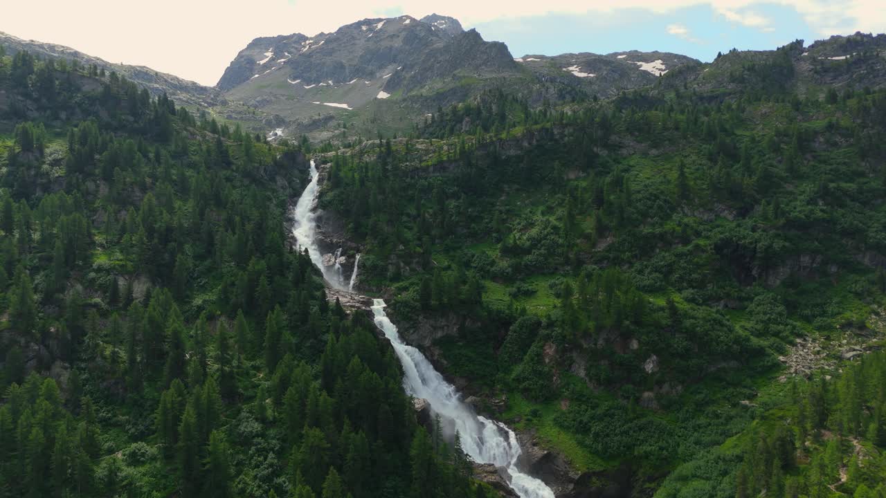 majestuosas cascadas a través de los exuberantes verdes alpes italianos, picos de montañas en el fondo