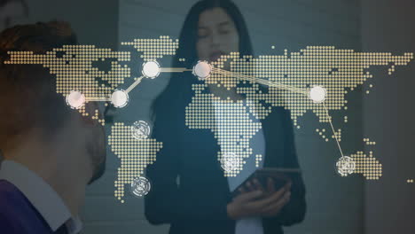 man wearing glasses and woman holding tablet presenting world map network in business tech office