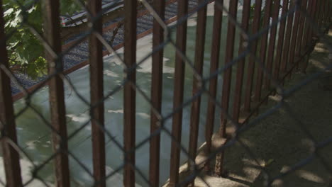 el tren subterráneo pasa por una vía cercana vista desde arriba a través de una cerca en una tarde parcialmente soleada en brooklyn, nueva york