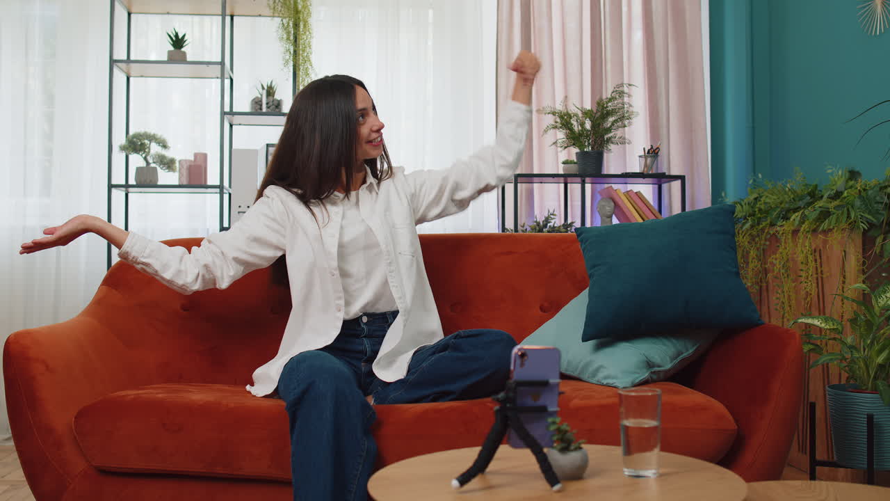 소녀 블로거는 기기 화면을 보고 스마트폰으로 셀카를 찍고 가상 비디오 춤 콘텐츠를 만 ⁇ 니다.