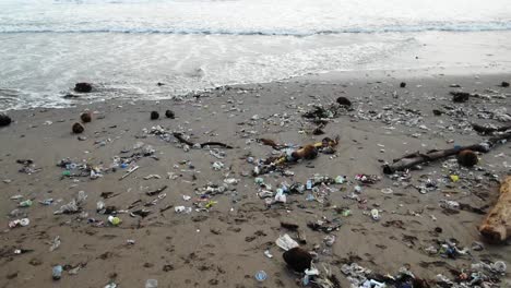 camera moves over plastic garbage washed out to the shore from the ocean, man kind polluted the seas