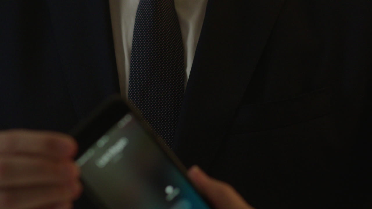 Man in suit adjusting his phone in pocket