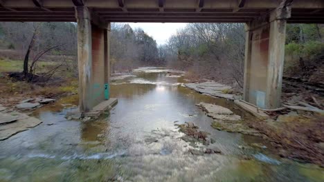 aerial shot flying under a bridge at sunset in the fall, in monterey kentucky over cedar creek