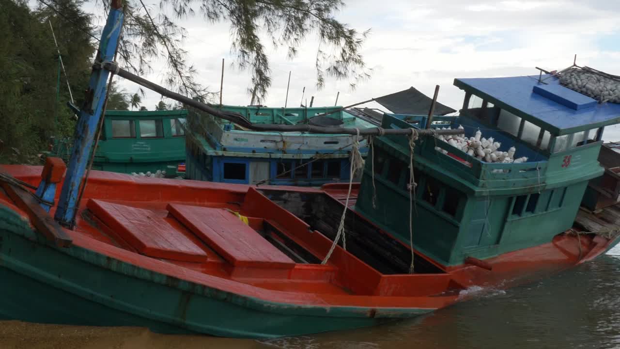 una toma panorámica lenta de un viejo barco de pescadores en la orilla de una playa en un día lluvioso recortada