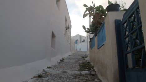 a man is walking up an alley in a greek cycladic village