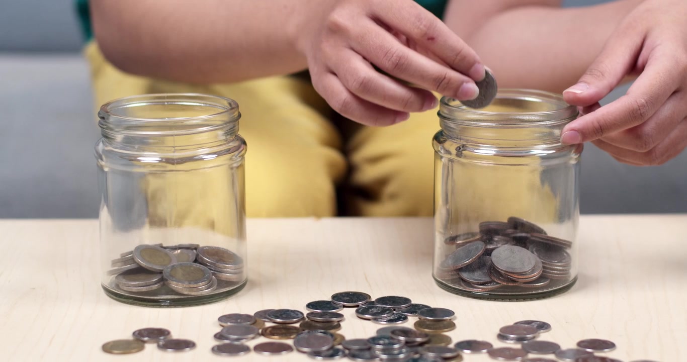 A person saving coins in a jar showing importance of budgeting and financial management.